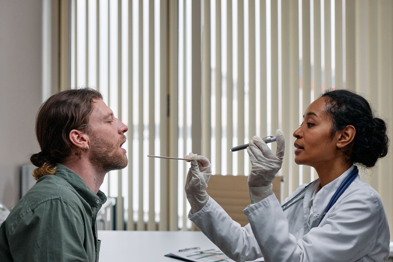 A doctor examining a patient's throat with a tongue depressor during a same-day appointment.